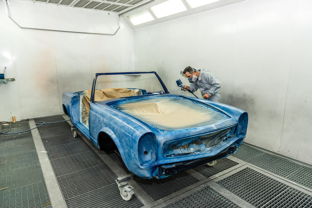 Ein Lackierer lackiert einen Oldtimer in blauer Farbe