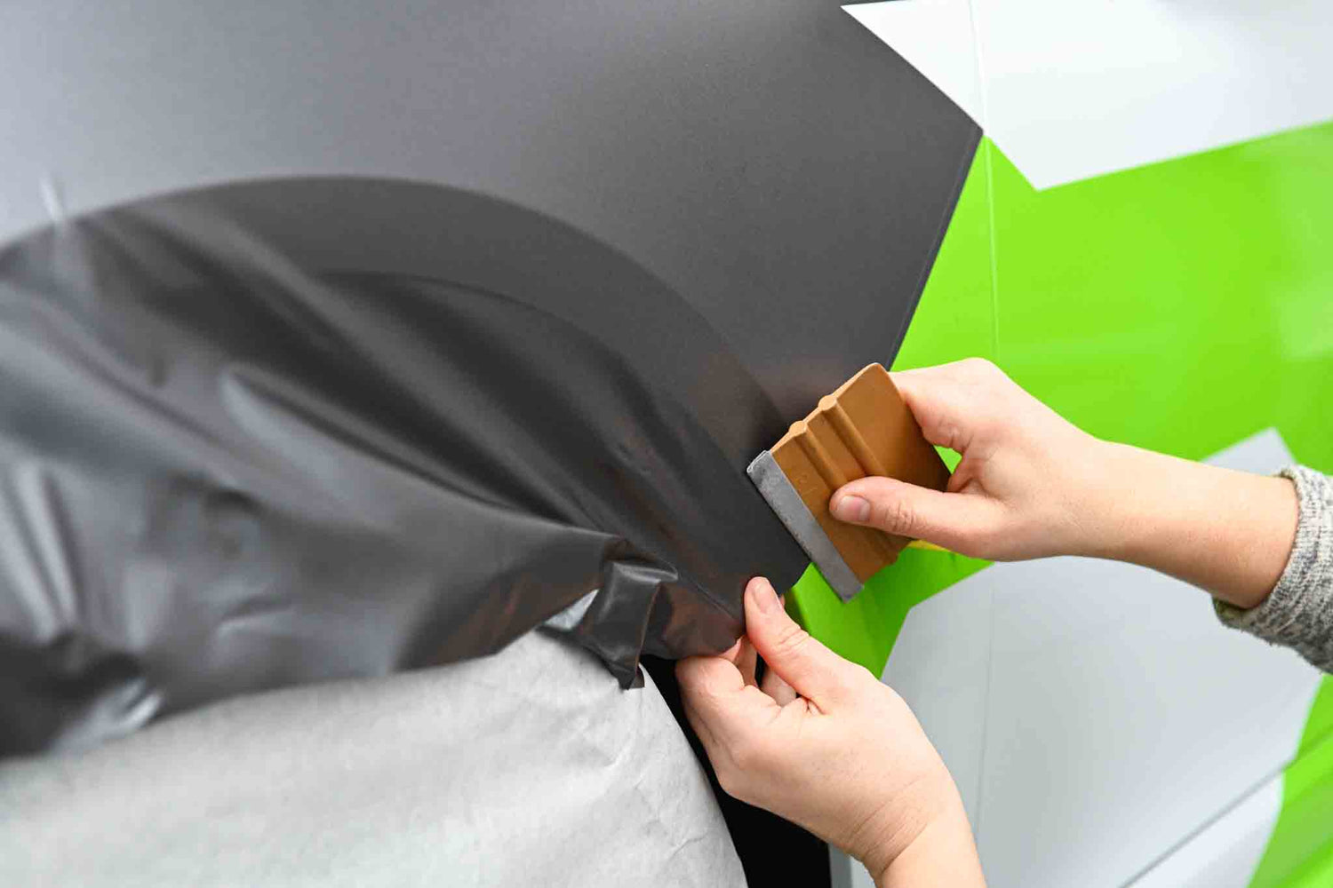 Eine Folie wird auf ein Auto foliert. Car-Wrapping Arbeit